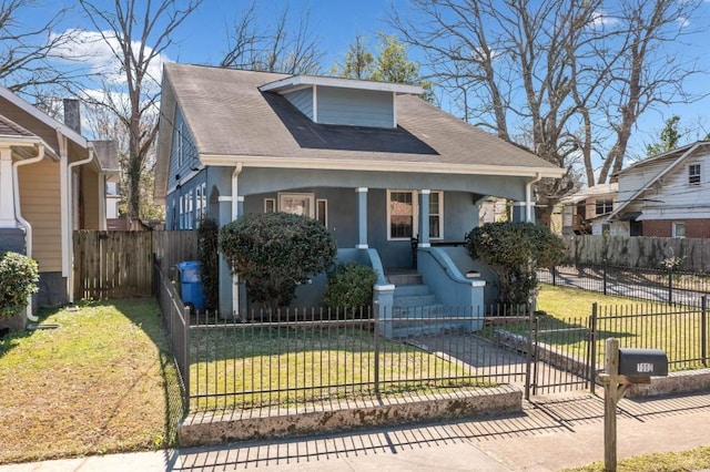 bungalow featuring a fenced front yard, a porch, a front lawn, and stucco siding