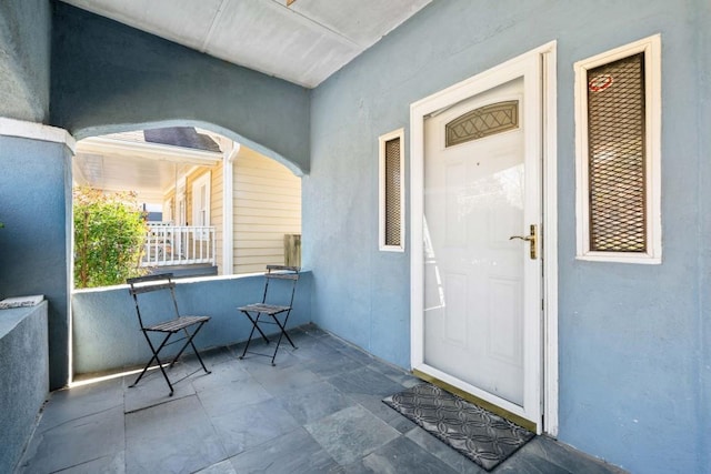 view of exterior entry featuring stucco siding and a porch