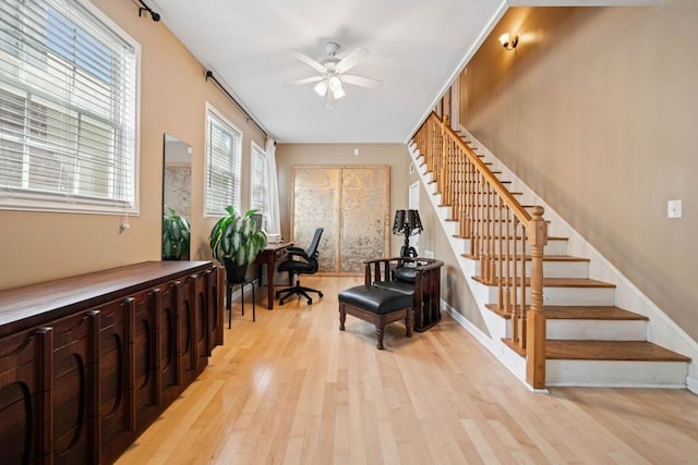 foyer with ceiling fan, baseboards, stairs, and light wood-style floors