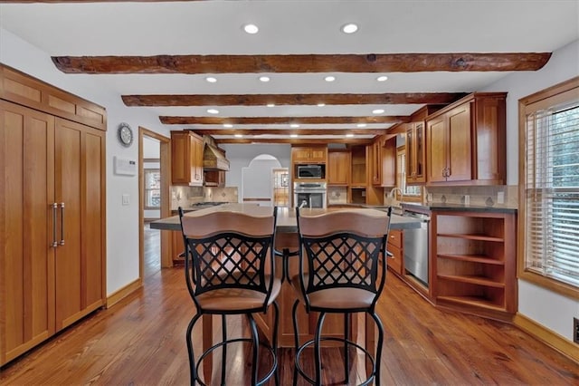 kitchen featuring wood-type flooring, stainless steel appliances, a kitchen breakfast bar, and a center island with sink