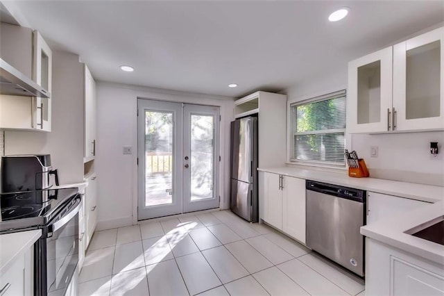 kitchen featuring wall chimney exhaust hood, french doors, white cabinetry, and stainless steel appliances