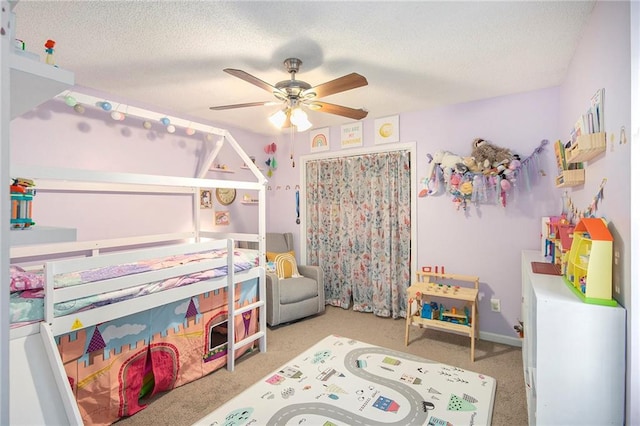 carpeted bedroom with ceiling fan, a textured ceiling, and a closet