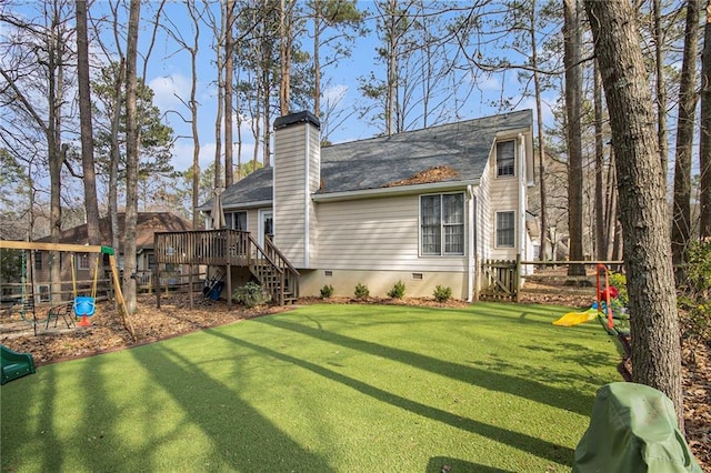 back of property with a playground, a wooden deck, and a yard