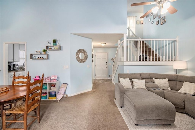 carpeted living room featuring ceiling fan and a towering ceiling