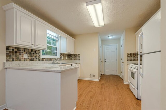 kitchen with white appliances, white cabinetry, light hardwood / wood-style flooring, and decorative backsplash