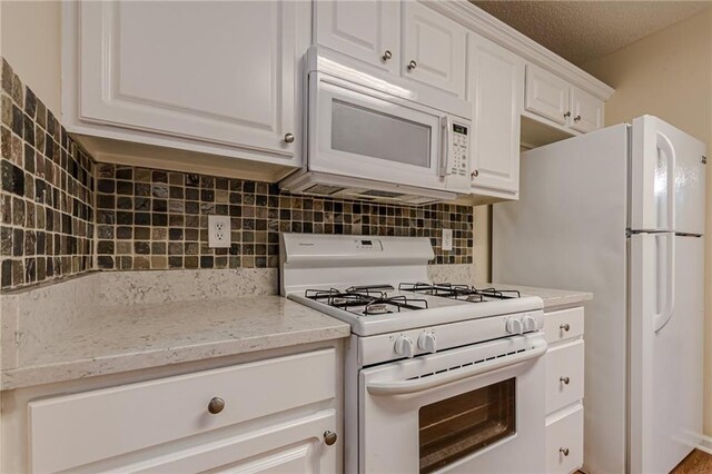 kitchen featuring backsplash, a textured ceiling, white cabinetry, light stone counters, and white appliances