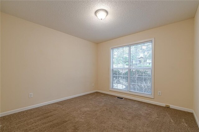 carpeted empty room with a textured ceiling