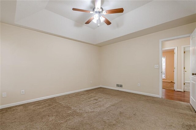 carpeted empty room with a tray ceiling and ceiling fan