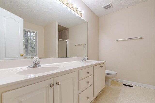 bathroom with vanity, a textured ceiling, toilet, and an enclosed shower