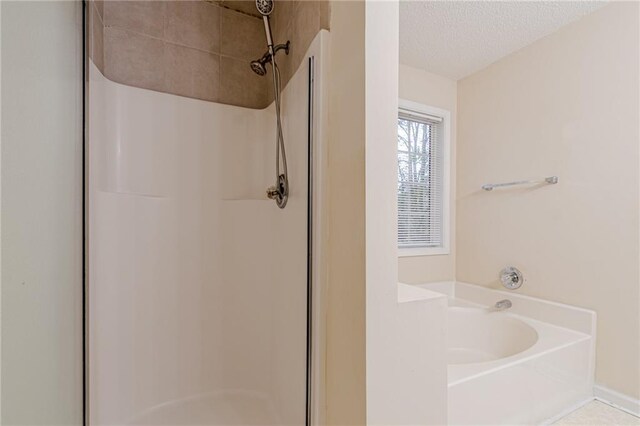 bathroom with a textured ceiling and shower with separate bathtub