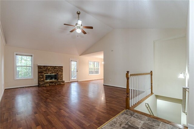 unfurnished living room with a stone fireplace, dark hardwood / wood-style flooring, and plenty of natural light