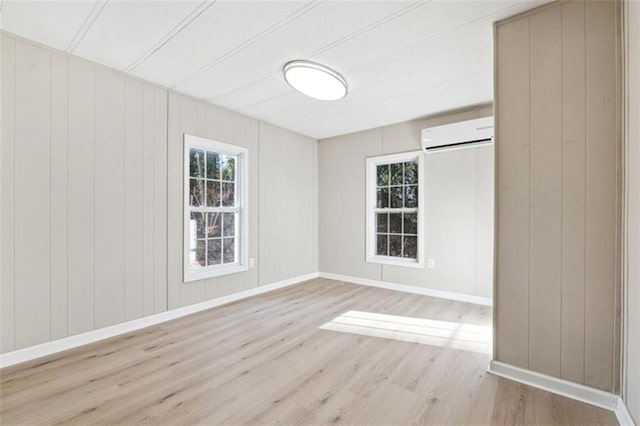 spare room featuring an AC wall unit, wood walls, and light hardwood / wood-style flooring