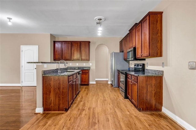 4499 Bellemeade Dr, Douglasville, GA 30135 - kitchen with arched walkways, light wood-style flooring, appliances with stainless steel finishes, and a sink
