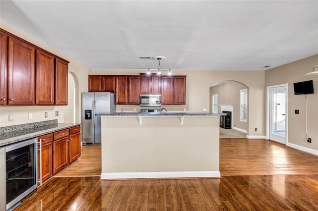 4499 Bellemeade Dr, Douglasville, GA 30135 - kitchen featuring arched walkways, wood finished floors, stainless steel appliances, and wine cooler