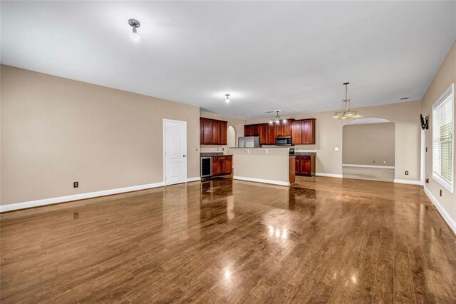 4499 Bellemeade Dr, Douglasville, GA 30135 - unfurnished living room featuring an inviting chandelier, baseboards, arched walkways, and dark wood finished floors