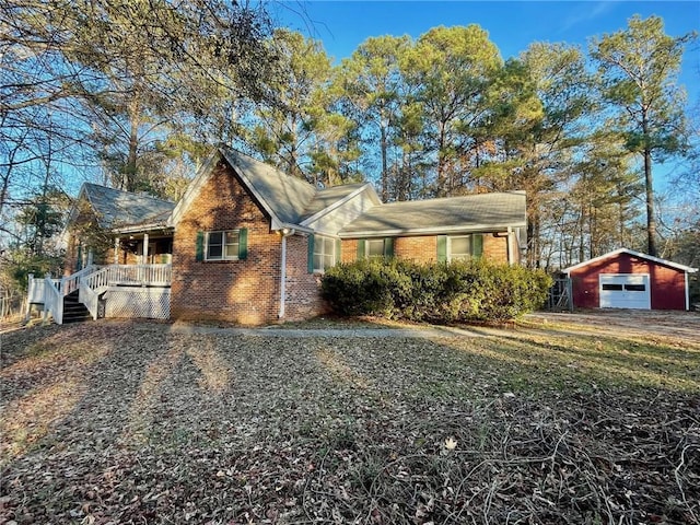 view of front of house with brick siding, a garage, an outbuilding, and covered porch
