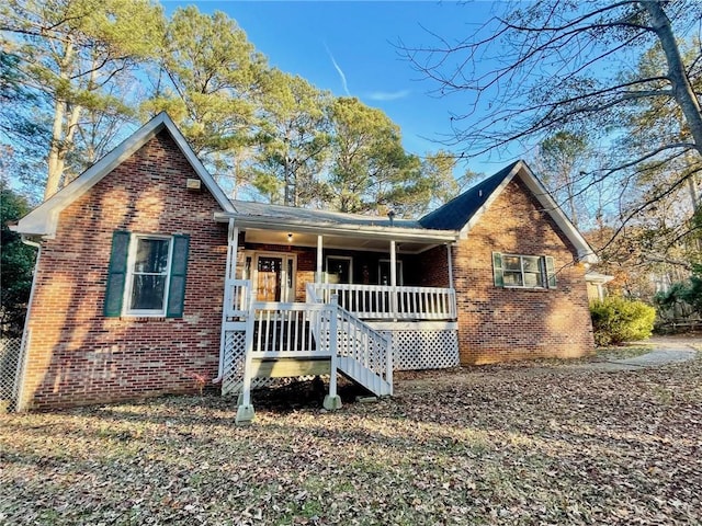 view of front of house with covered porch, brick siding, and stairs