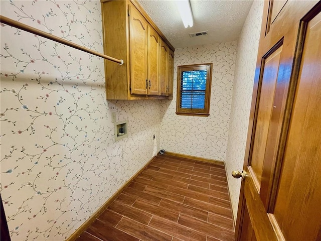 clothes washing area with visible vents, dark wood-style flooring, hookup for a washing machine, a textured ceiling, and cabinet space
