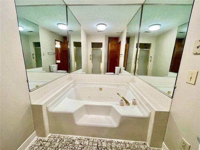 bathroom with baseboards, a shower stall, and a tub with jets