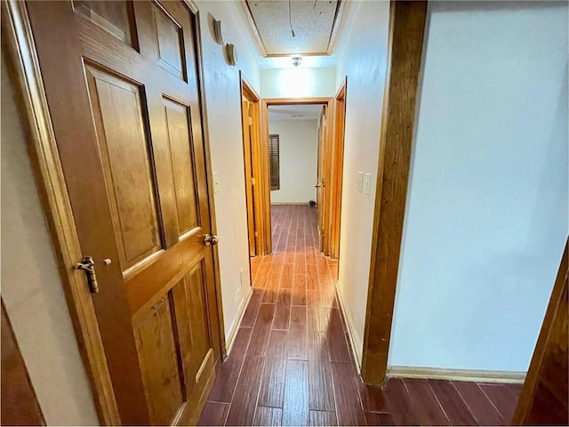 hall with baseboards, attic access, and dark wood-type flooring