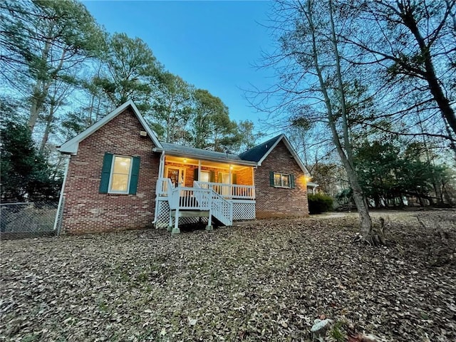 exterior space with brick siding, fence, and a porch