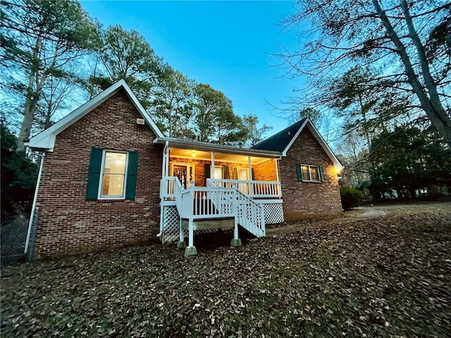 rear view of house with covered porch and brick siding