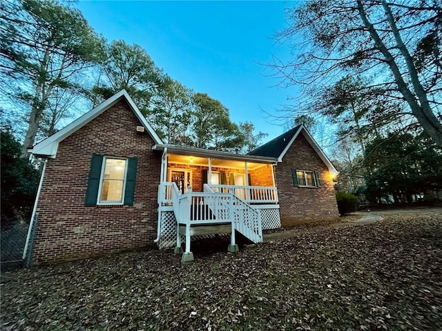 rear view of house featuring a porch and brick siding
