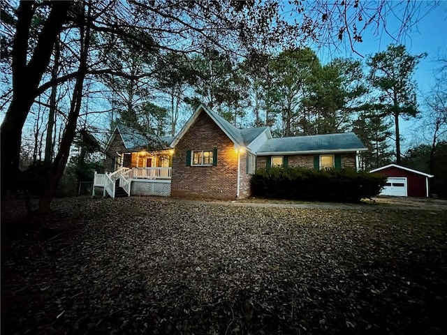 view of front of house featuring brick siding, a garage, a wooden deck, stairway, and an outdoor structure
