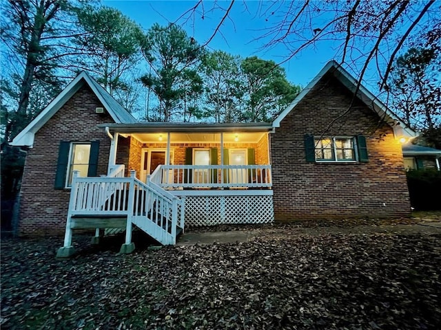 rear view of house with brick siding and a porch