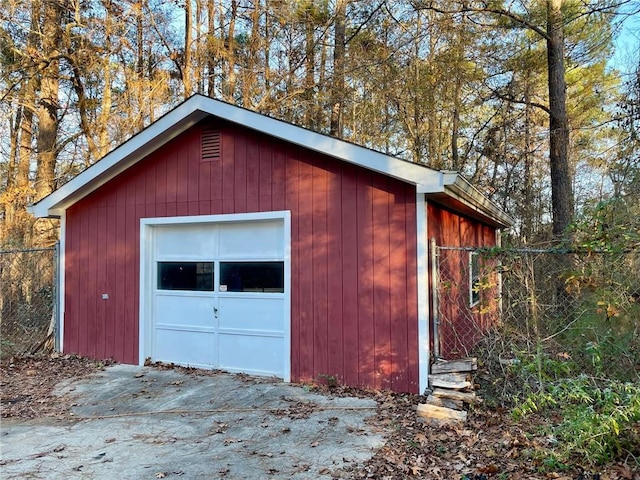 garage featuring fence and concrete driveway