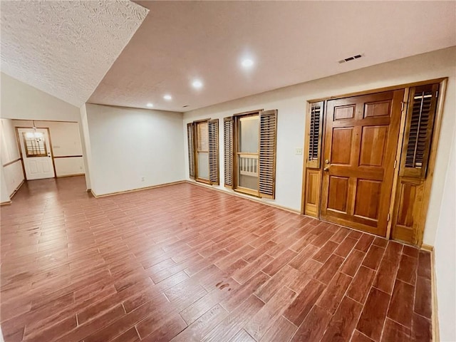 unfurnished living room with a textured ceiling, visible vents, wood finished floors, baseboards, and recessed lighting
