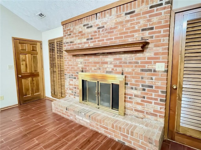 details featuring a textured ceiling, visible vents, a fireplace, wood finished floors, and baseboards