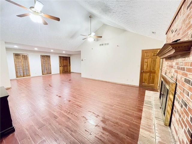 unfurnished living room with visible vents, a fireplace, ceiling fan, high vaulted ceiling, and light wood-type flooring