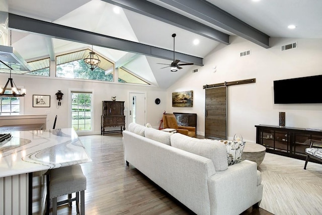 living room featuring light wood-type flooring, beamed ceiling, high vaulted ceiling, ceiling fan with notable chandelier, and a barn door