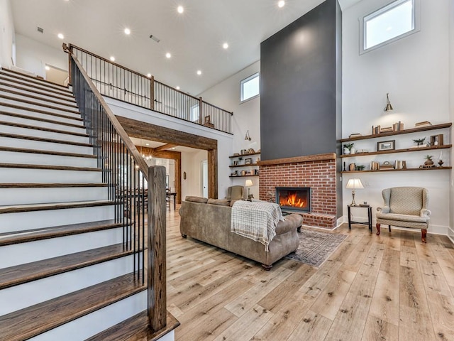 living room featuring a fireplace, a high ceiling, and light wood-type flooring