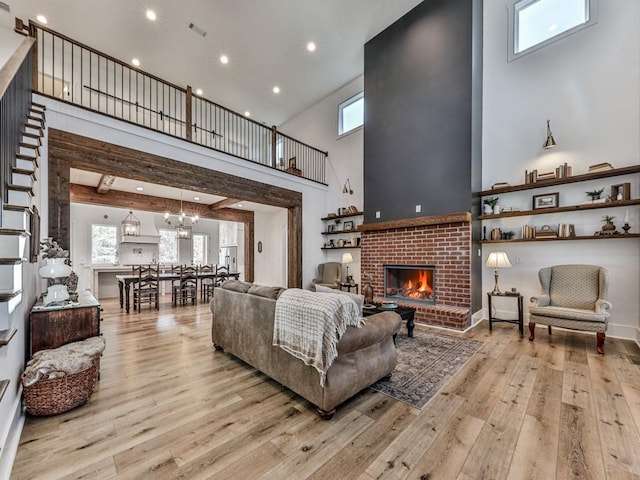 living room with beam ceiling, light hardwood / wood-style floors, a fireplace, and a high ceiling