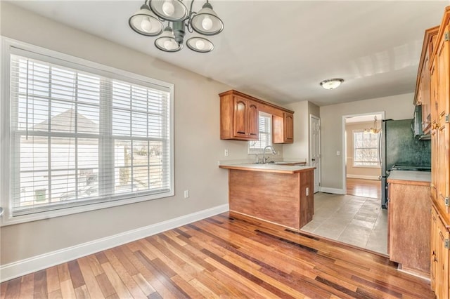 kitchen with a chandelier, sink, kitchen peninsula, and light wood-type flooring