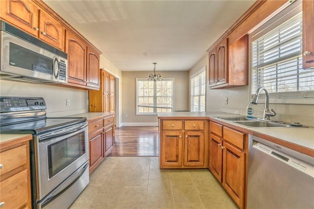 kitchen featuring sink, light tile patterned floors, a notable chandelier, pendant lighting, and stainless steel appliances