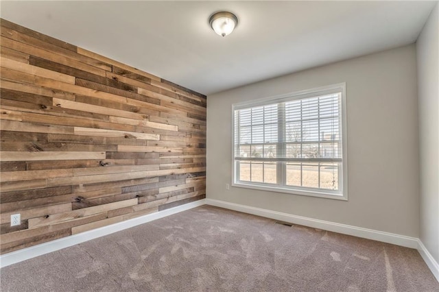 carpeted spare room featuring wood walls