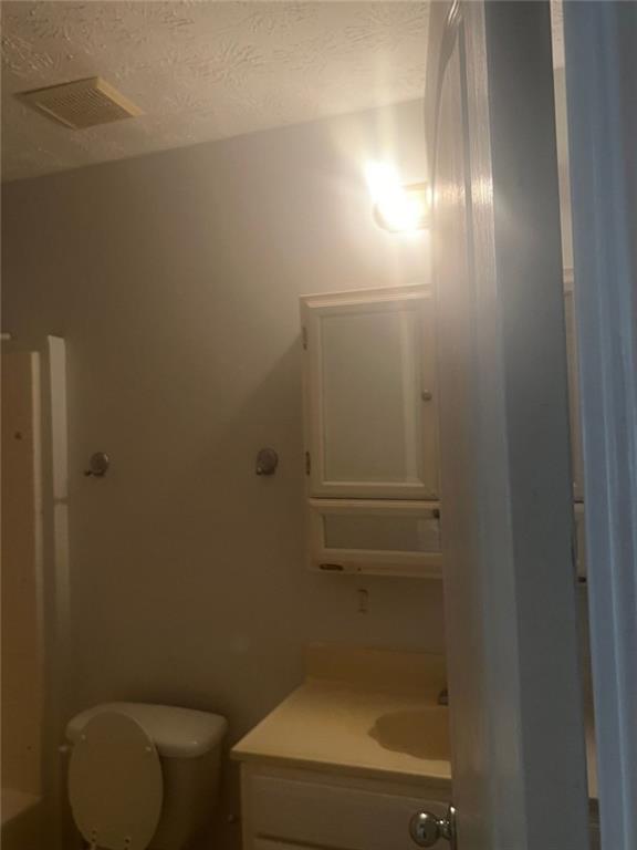 bathroom featuring vanity, a textured ceiling, and toilet