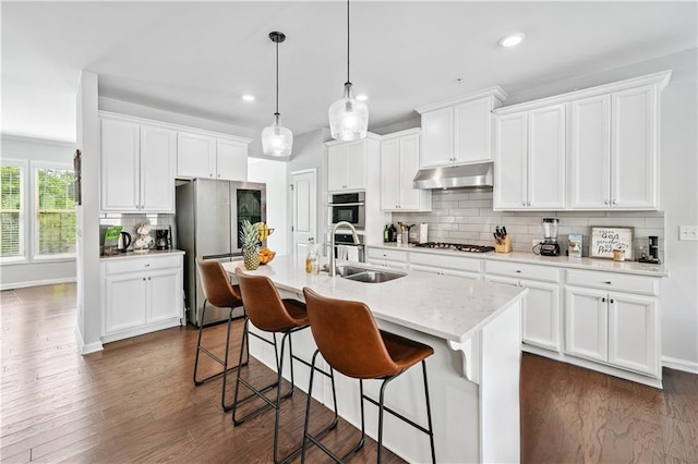 350 Provenance Dr, Atlanta, GA 30328 - kitchen featuring under cabinet range hood, stainless steel appliances, dark wood-style flooring, backsplash, and a breakfast bar