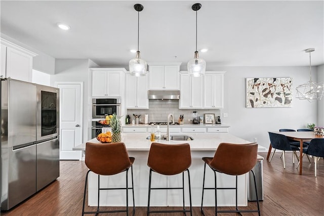 350 Provenance Dr, Atlanta, GA 30328 - kitchen featuring appliances with stainless steel finishes, under cabinet range hood, tasteful backsplash, light countertops, and a breakfast bar
