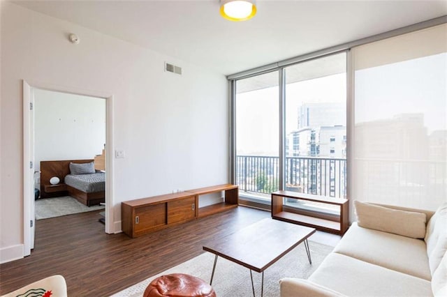 living area with baseboards, floor to ceiling windows, visible vents, and dark wood-type flooring