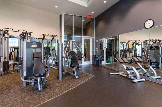 gym featuring floor to ceiling windows, a high ceiling, and recessed lighting