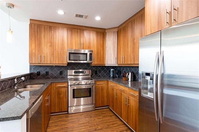 kitchen with visible vents, brown cabinetry, appliances with stainless steel finishes, hanging light fixtures, and a sink