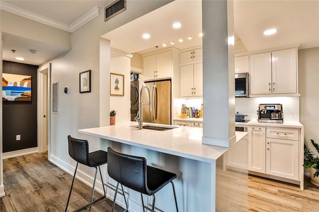 kitchen with visible vents, light wood finished floors, a breakfast bar, white cabinets, and appliances with stainless steel finishes