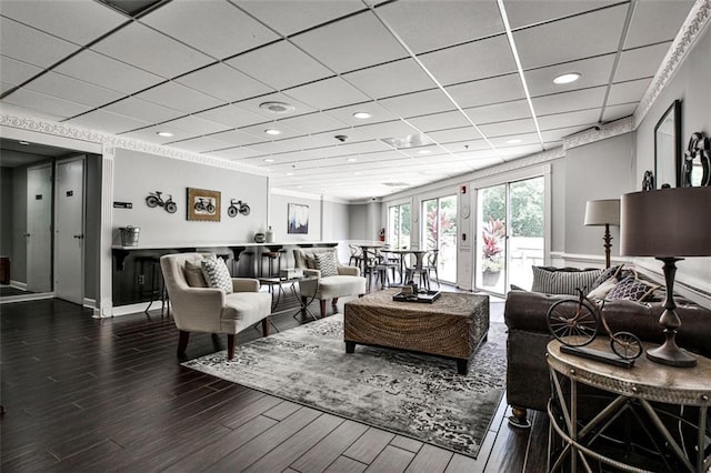 living room featuring a drop ceiling, recessed lighting, baseboards, and wood finished floors