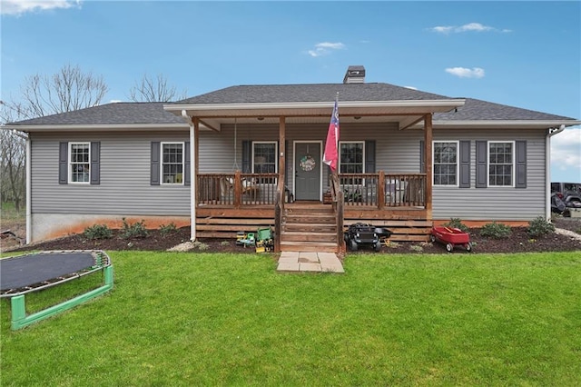 back of property with a yard, a porch, a chimney, and roof with shingles