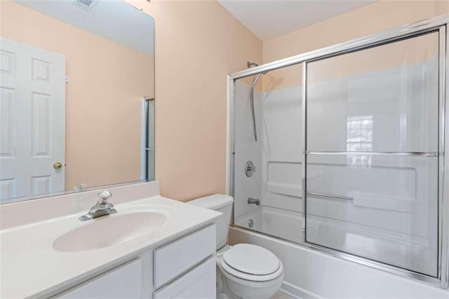 full bathroom featuring vanity, bath / shower combo with glass door, and toilet