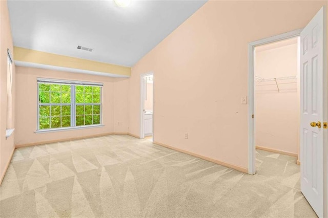 empty room featuring vaulted ceiling and light colored carpet